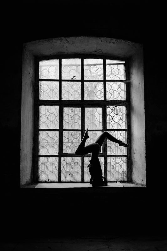 Κοπέλα που κάνει γιόγκα μπροστά σε παράθυρο